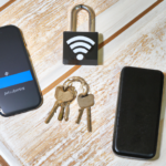 wifi router on a desk next to a set of keys on a keychain, and a smartphone